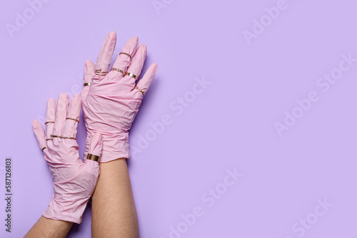 Woman in pink gloves with rings on lilac background
