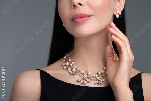 Young woman with elegant jewelry on dark grey background, closeup