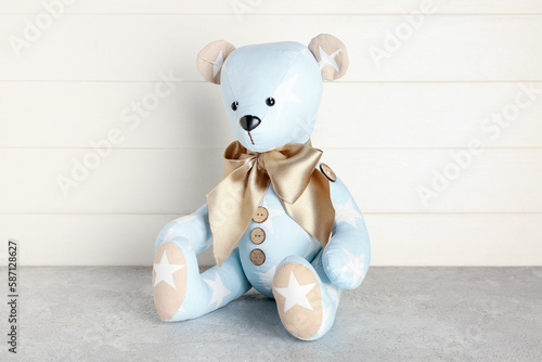 Toy bear on table near white wooden wall