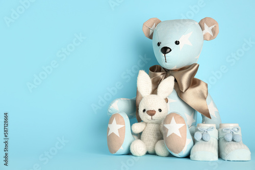 Toy bear and bunny with baby socks on blue background