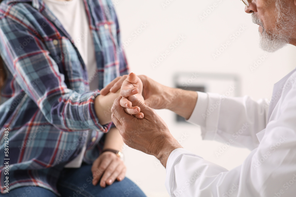 Orthopedist examining patient with injured hand in clinic, closeup