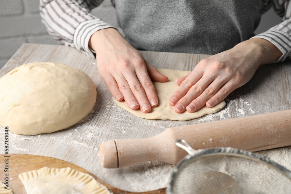 Fototapeta premium Woman making chebureki at wooden table, closeup