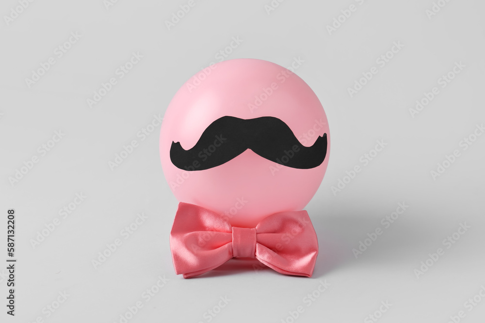 Naklejka premium Composition with balloon, paper mustache and bow tie on grey background