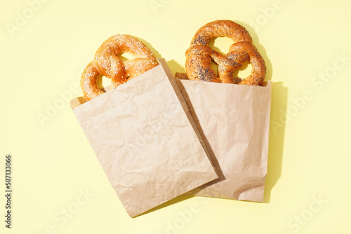 Paper bags with tasty pretzels on color background photo