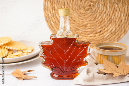 Beautiful composition with bottle of maple syrup and waffles on white background