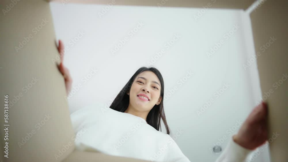 Surprised young asian woman unpacking. Opening carton box and looking inside. Packaging box, delivery service. Human emotions and facial expression Surprised young asian woman unpacking. Opening carton box and looking inside. Packaging box, delivery service. Human emotions and facial expression