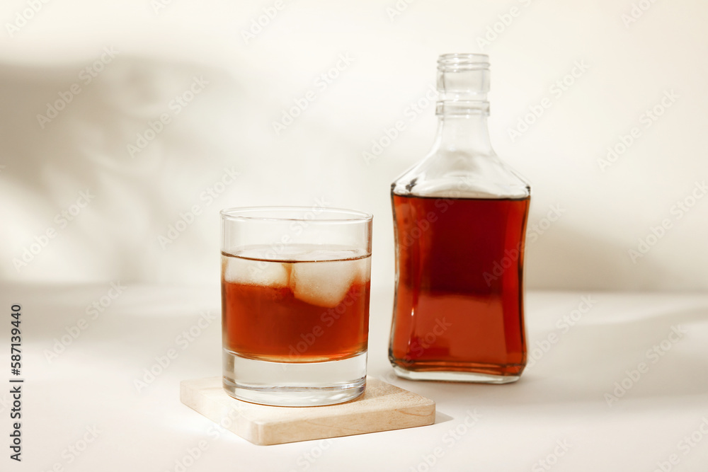 Bottle and glass of cold rum on beige background Bottle and glass of cold rum on beige background