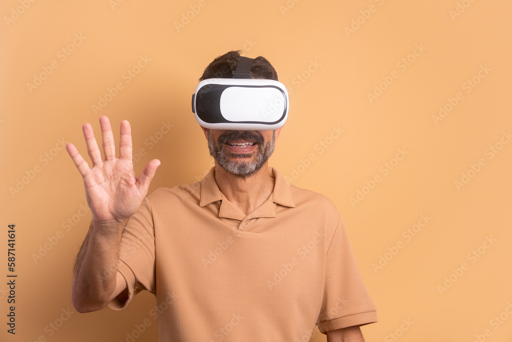 happy brazilian man Using VR headset and gesturing in beige studio background. virtual reality, technology simulation concept. happy brazilian man Using VR headset and gesturing in beige studio background. virtual reality, technology simulation concept.