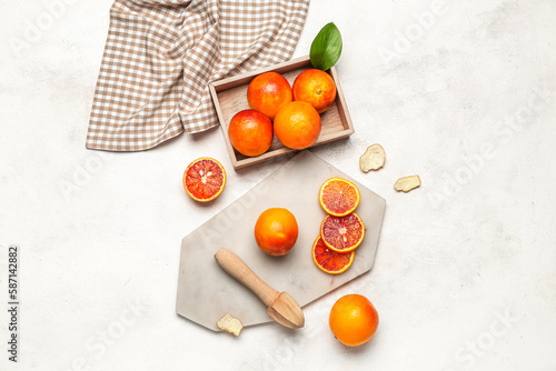 Box and board with tasty blood oranges on white background