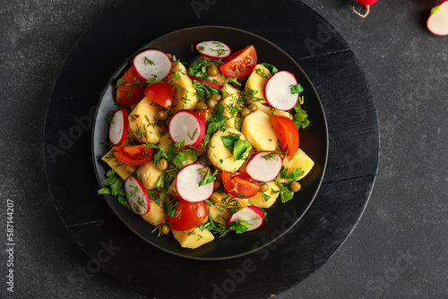 Plate of tasty Potato Salad with vegetables on dark background
