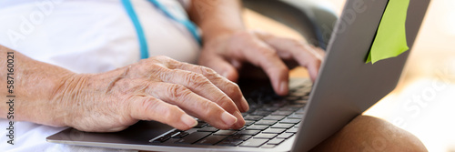 Elderly woman typing on laptop is looking for information on Internet