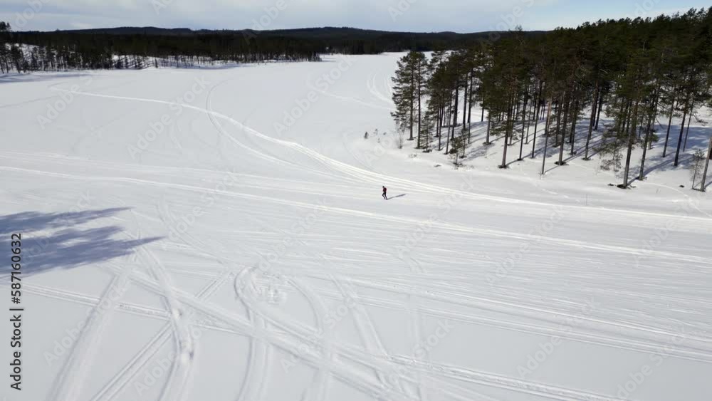A runner who is running on a snow covered frozen lake on a cold sunny winter day. Orbiting drone footage. A runner who is running on a snow covered frozen lake on a cold sunny winter day. Orbiting drone footage.