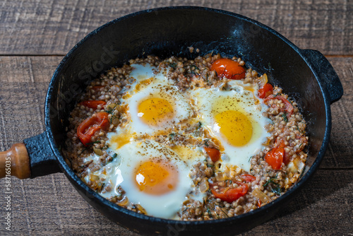 Boiled buckwheat with fried eggs, red peppers, tomato and onions, closeup, Ukraine. Food background. Healthy food