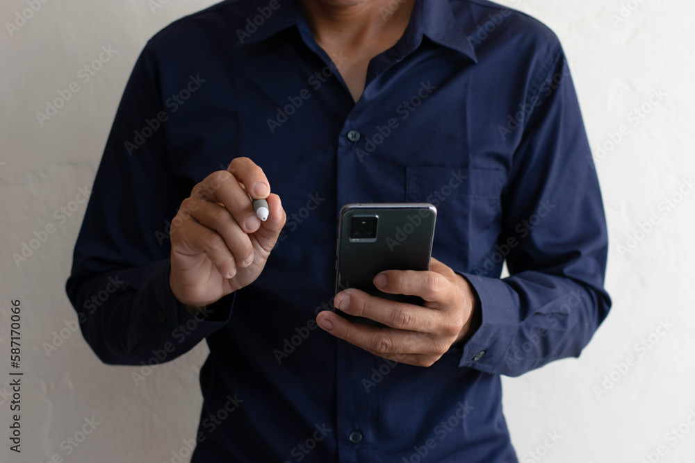Man using mobile phone to talk online, holding pen to work, contemplating plans for work Man using mobile phone to talk online, holding pen to work, contemplating plans for work