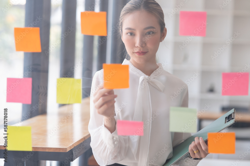 Young Asian businesswoman holding a note on the board presenting about financial business Young Asian businesswoman holding a note on the board presenting about financial business