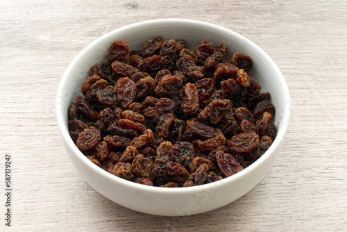 Dried fruit sultana raisins in a bowl on wooden background.