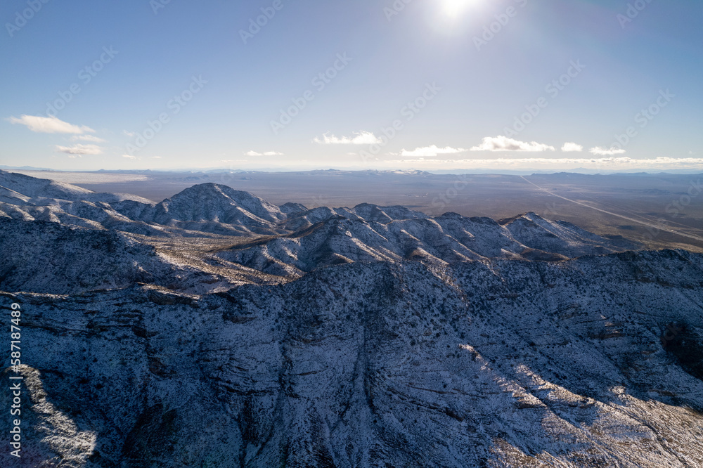 Aerial view of highway in California after snow storm with traffic. Trucks and cars are going on interstate along mountains and deserts.