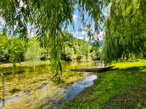 small boat on the shore of a green lake