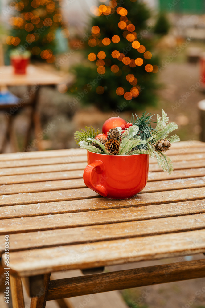 Vertical shot of a red mug with artificial fir twigs and cones on a wooden table. Vertical shot of a red mug with artificial fir twigs and cones on a wooden table.