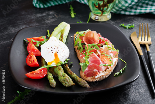 Keto breakfast. Fried asparagus with poached egg and toast with prosciutto or jamon. Ketogenic diet. Healthy food.