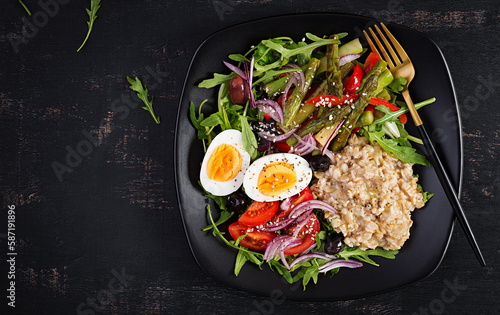 Breakfast oatmeal porridge with boiled egg, cherry tomatoes, asparagus and arugula. Healthy balanced food. Top view, overhead