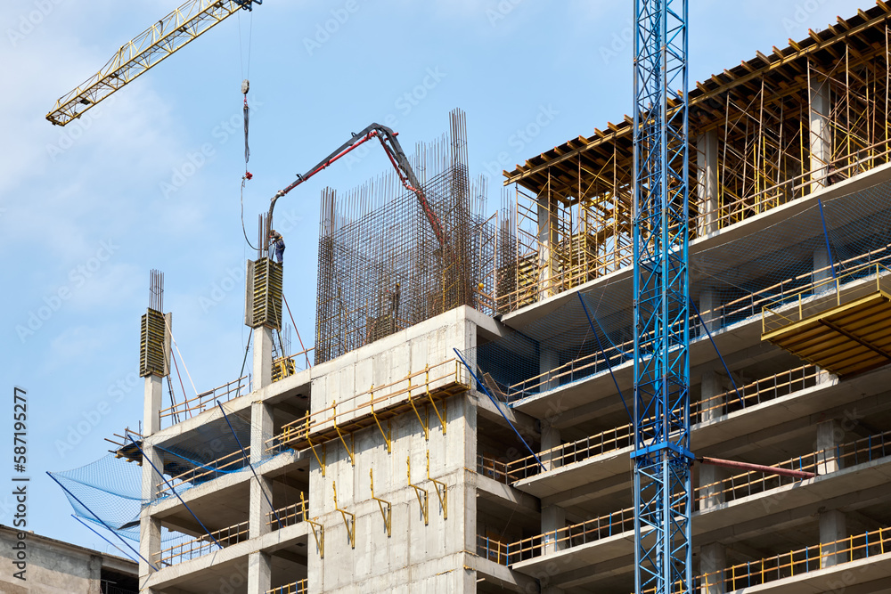 Workers pour concrete at the construction site of a new building. Workers pour concrete at the construction site of a new building.