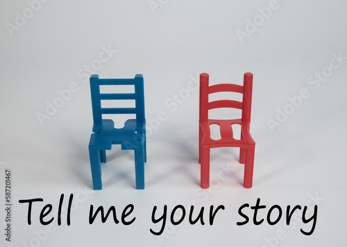 Kolorowe, różne krzesła ułożone bokami do siebie. Napis TELL ME YOUR STORY. Koncepcja budowania relacji.