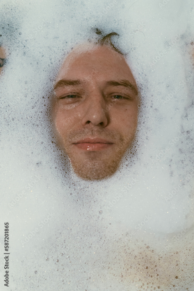 Young tattooed man laying in bubble bath. Young tattooed man laying in bubble bath.