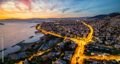 Panoramic aerial view of the Athens Riviera coastline with Voula suburb and Vouliagmenis street during dusk with traffic light trails, Greece