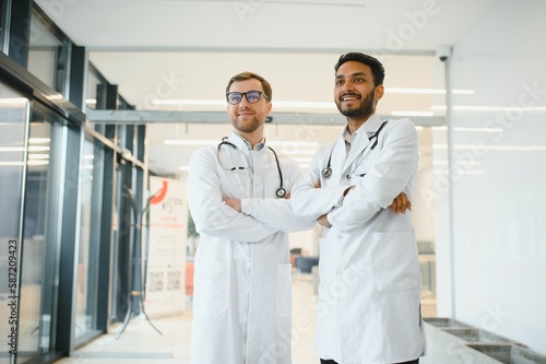 An Indian doctor and a European doctor stand together in a hospital lobby.