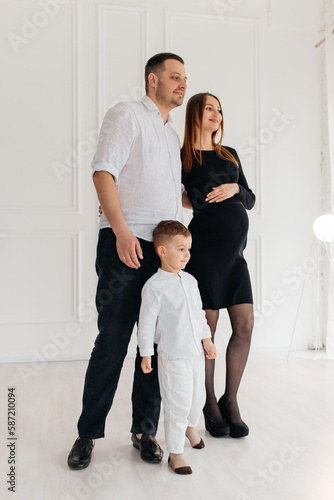 Beautiful pregnant woman with her family on light background © stenkovlad