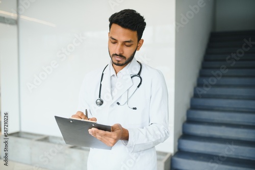 Portrait of confident Asian Indian medical doctor standing at hospital building