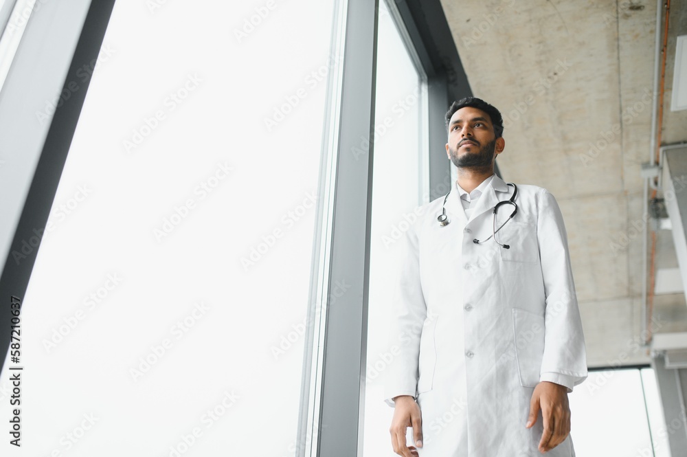 Fototapeta premium Portrait of confident Asian Indian medical doctor standing at hospital building