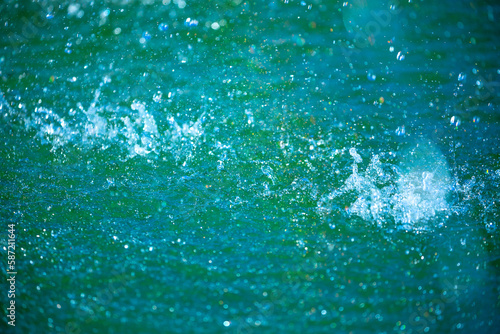 Water background, blue sea water. Beautiful texture of sun glare on the water and sea foam.