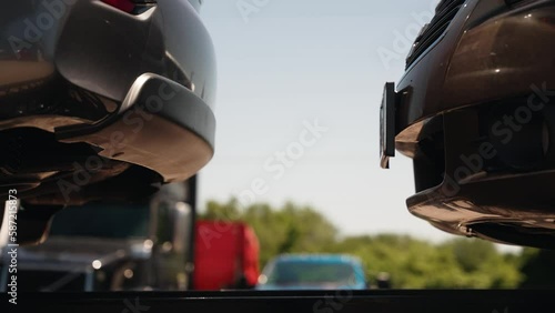 front bumper almost touching rear bumper of a car. Auto vehicles are on a carhauler wedge trailer. photo