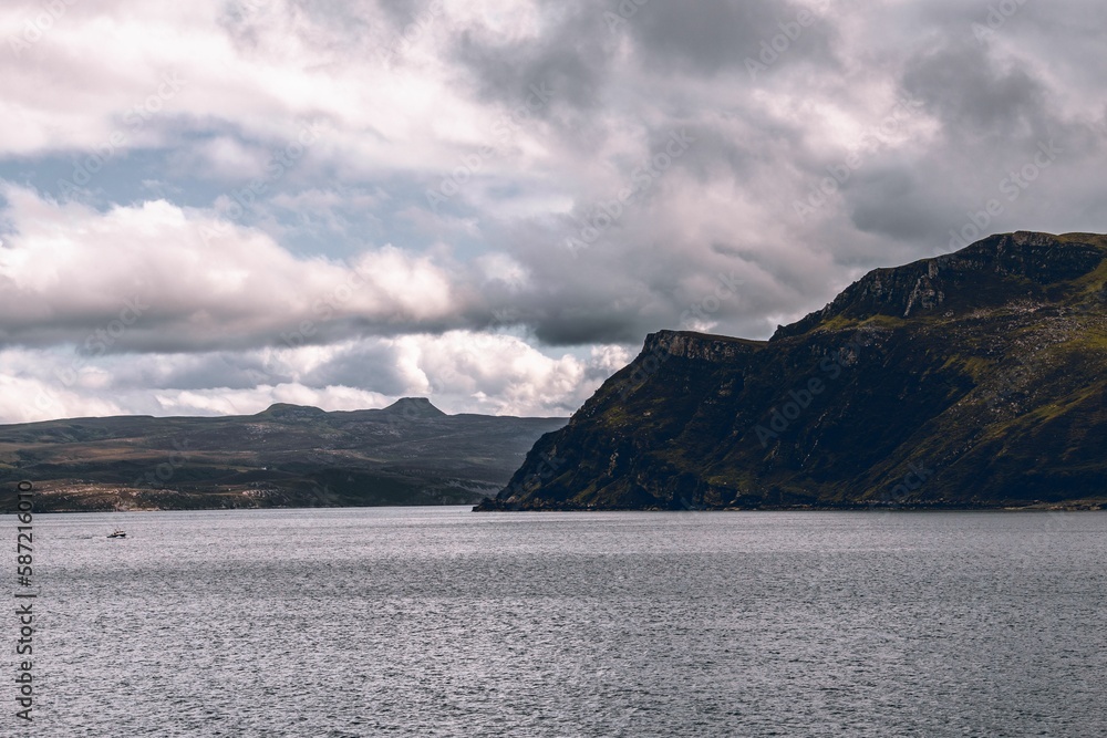 Beautiful shot of the historic Isle of Skye cliff over the water under a cloudy sky in Scotland