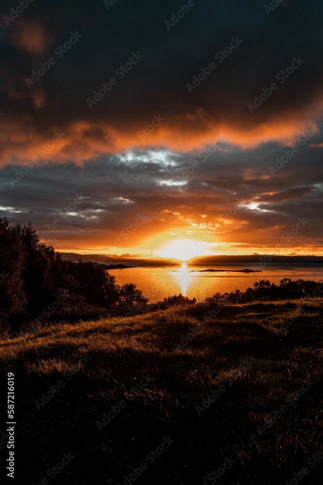 Vertical shot of a bright orange sunset sky over the water in Isle of Skye, Scotland