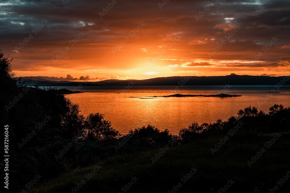 Beautiful shot of a bright orange sunset sky over the water in Isle of Skye, Scotland