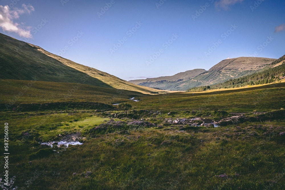 Obraz premium Wide horizontal shot of a landscape in Ilse of Skye, Scotland, with a small waterfall in the middle