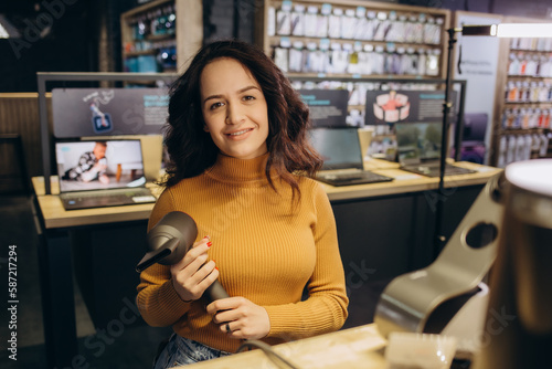 Beautiful woman in the store is testing a hairdryer.