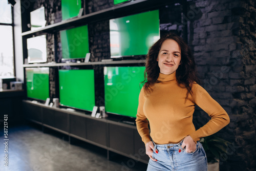 a woman in an electronics store chooses a TV on the background of TVs with a green screen