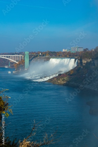 Vertical distant shot of Niagara Falls and the Rainbow Bridge under the blue sky