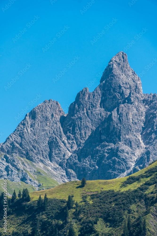 Fototapeta premium Vertical shot of a mountain with a clear blue sky in the background