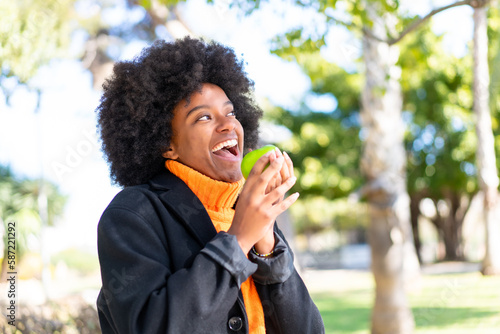 African American girl at outdoors holding an apple with happy expression