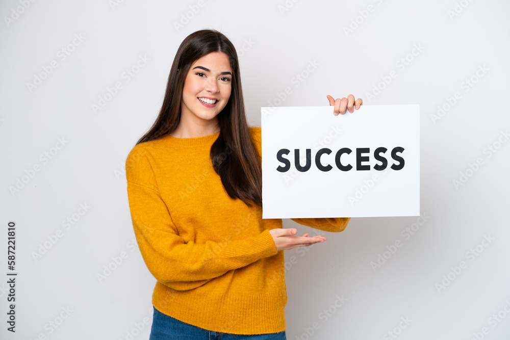 Young Brazilian woman isolated on white background holding a placard with text SUCCESS with happy expression Young Brazilian woman isolated on white background holding a placard with text SUCCESS with happy expression