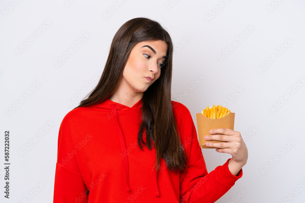 Young Brazilian woman catching french fries isolated on white background with sad expression Young Brazilian woman catching french fries isolated on white background with sad expression
