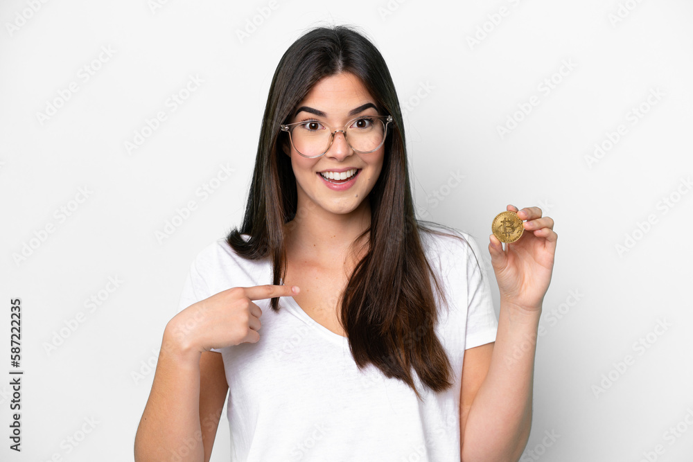 Young Brazilian woman holding a Bitcoin isolated on white background with surprise facial expression Young Brazilian woman holding a Bitcoin isolated on white background with surprise facial expression