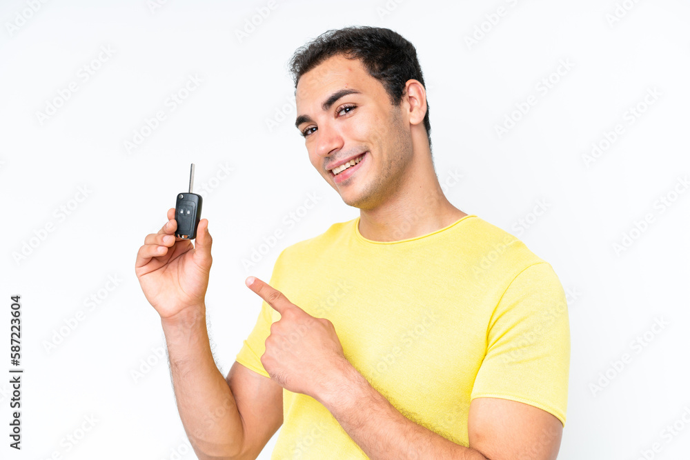 Young caucasian man holding car keys isolated on white background and pointing it Young caucasian man holding car keys isolated on white background and pointing it