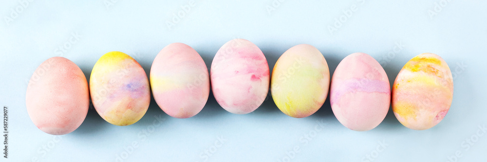 Painted Easter eggs in pink yellow and green on a blue background with a place for text. Happy Easter concept. Banner Painted Easter eggs in pink yellow and green on a blue background with a place for text. Happy Easter concept. Banner