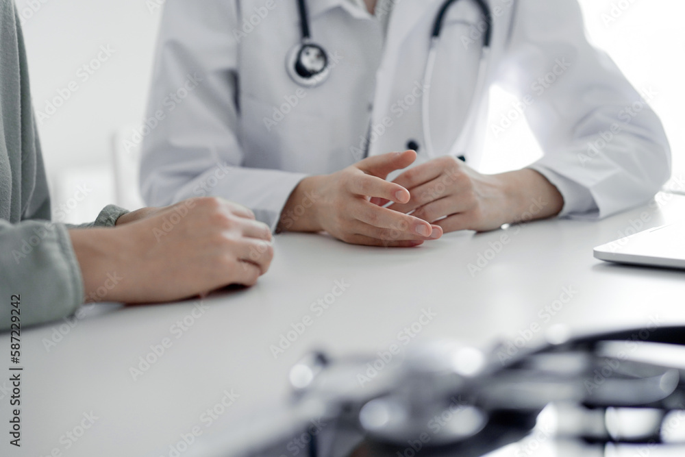 Doctor and patient discussing current health examination while sitting at the desk in clinic office, closeup. Perfect medical service and medicine concept. Doctor and patient discussing current health examination while sitting at the desk in clinic office, closeup. Perfect medical service and medicine concept.